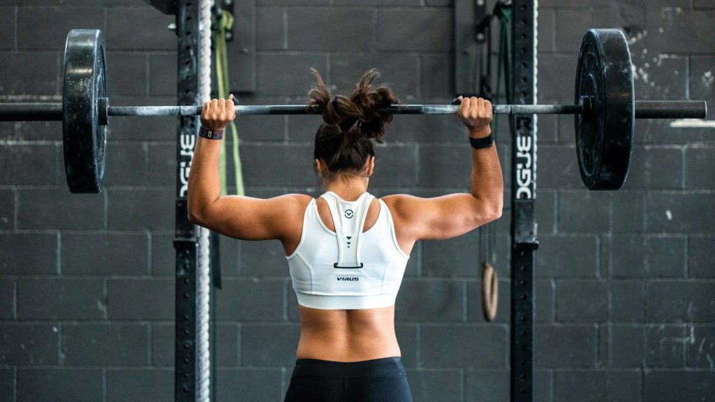 woman shoulder pressing a barbell