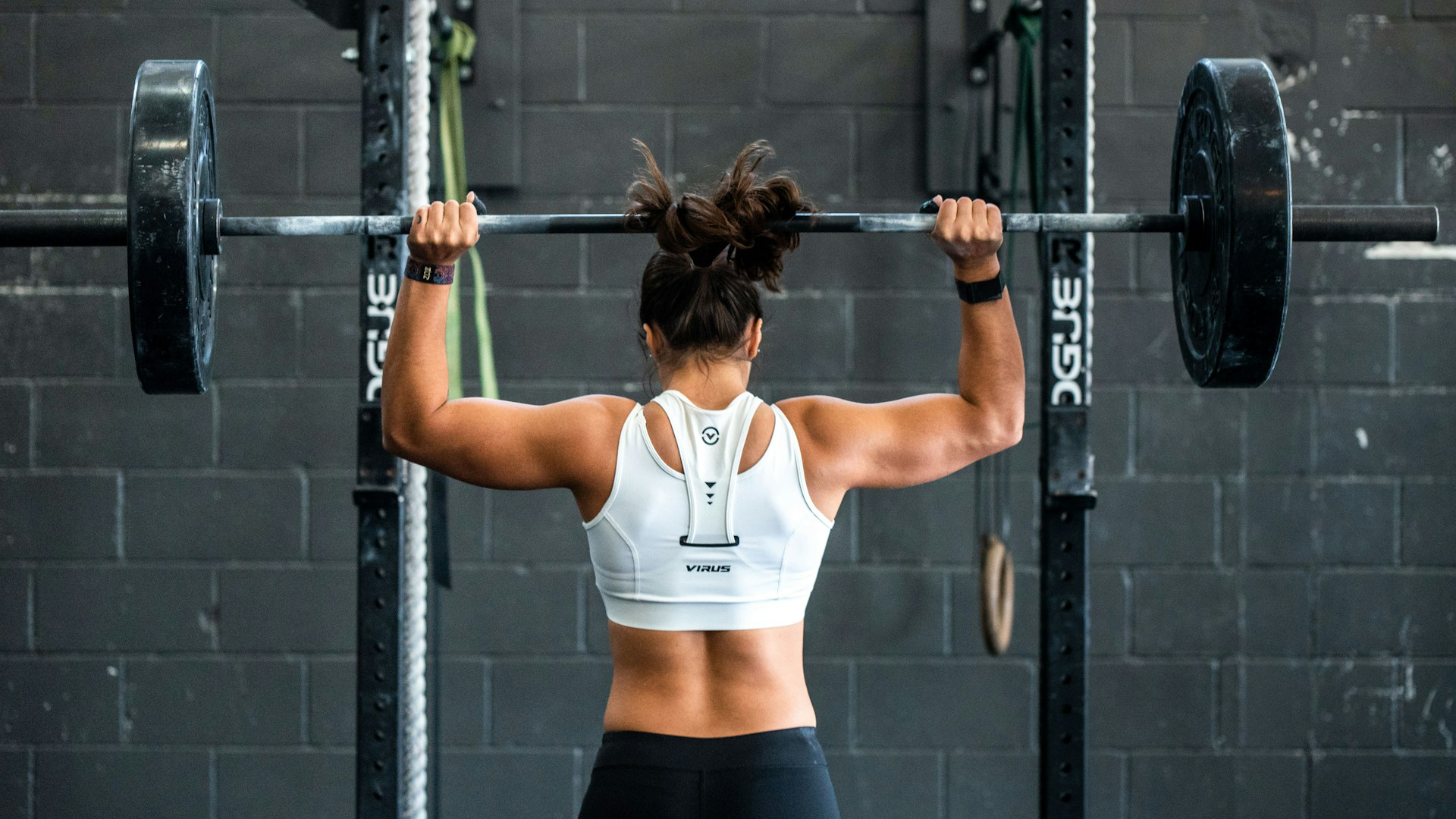 woman shoulder pressing a barbell