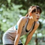 Young asian woman bent over resting after a run