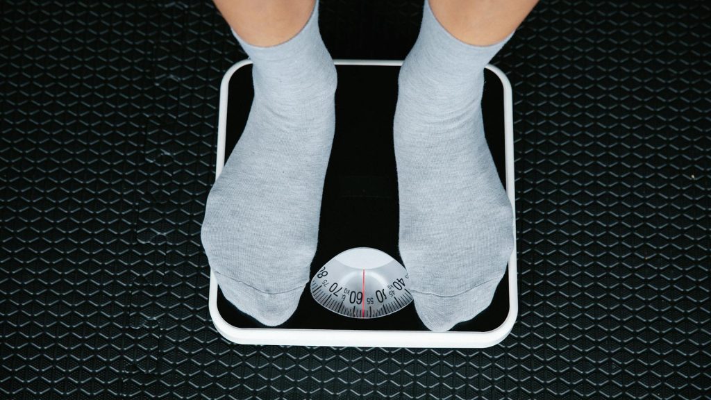 Feet in grey socks standing on an analog scale