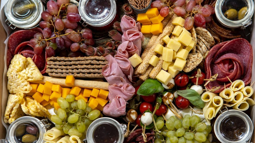 Charcuterie board with grapes, breads, cheeses, and cold cuts