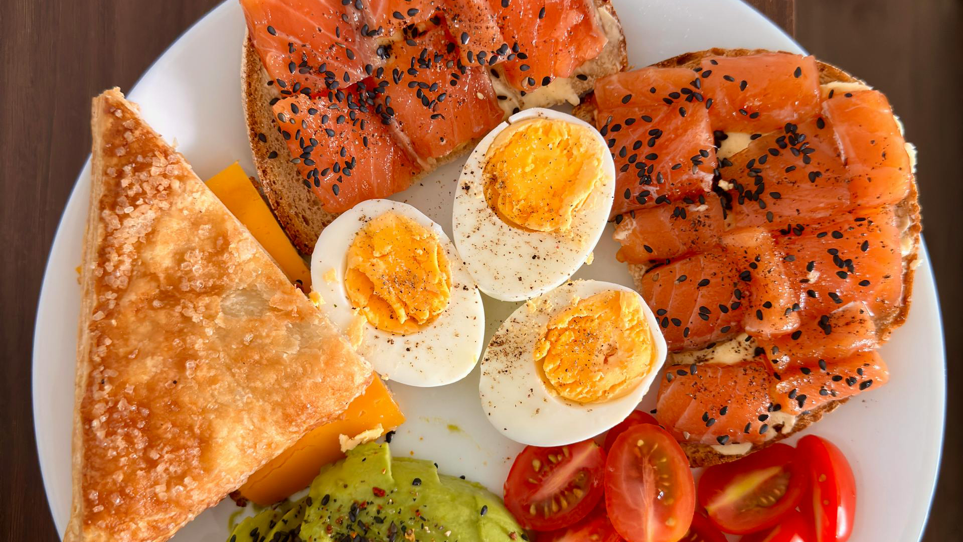 plate with hard boiled eggs, salmon, avocado, tomatoes, and toast